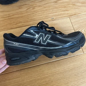 Svarta sneakers från New Balance - Säljer ett par svarta New Balance sneakers med silverdetaljer och snörning. Skorna har en sportig design med meshmaterial för bra ventilation och en robust sula för komfort. Perfekta för träning eller vardagsbruk.