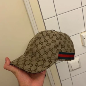 Beige keps från Gucci - Snygg beige keps från Gucci med det ikoniska GG-mönstret. Kepsen har en justerbar rem baktill och en klassisk skärm. Skriv vid fler frågor! 😌