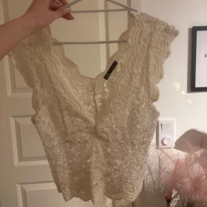 Vit spetslinne från Zara - Säljer ett vackert vitt spetslinne från Zara. Linnet har en djup v-ringning och är ärmlöst med fina spetsdetaljer. Bra skick men med anmärkning på att den är använd. 