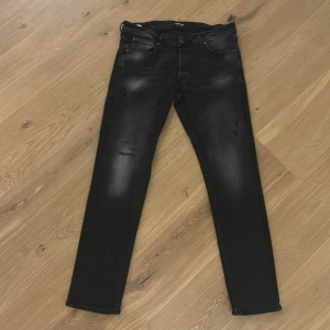 Svarta jeans från Jack & Jones - (34/32)Snygga svarta jeans från Jack & Jones med en modern slim passform. De har en klassisk femficksdesign och en diskret tvättning för en trendig look. Perfekta för en stilren vardagsstil.
