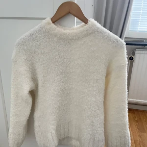 Vit fluffig tröja från Divided - Mysig vit fluffig tröja från Divided. Perfekt för kyliga dagar med sin mjuka och varma känsla. Tröjan har en enkel design med långa ärmar och rund halsringning. Storlek XXS men passar också S och M eftersom den är oversized.