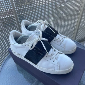 Valentino open sneakers  - Snygga vita Valentino open sneakers med en bred svart detalj över snörningen. Perfekta nu inför våren och sommaren, för en stilren look. Strolek 43 men passar även dig med storlek 42😊. Ny pris 5299kr mitt pris 2599kr. Box, kort, extra snören hänger med. frågor eller annat bara att skriva. 