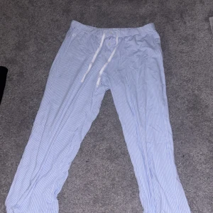 Randiga byxor från Ralph Lauren - Säljer ett par bekväma ljusblå och vita randiga byxor från Ralph Lauren. Byxorna har en midwaist design med snörning i midjan för justerbar passform. Använda ett fåtal gånge!