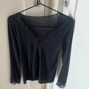 Svart intimissimi tröja med spets - Populär svart tröja från Intimissimi med v-ringning och spetsdetaljer vid hals och ärm. Endast använd två tre gånger och tvättad en gång så myckey bra skick, jag anser att den är som ny!
