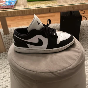 Svartvita Nike Air Jordans 1 - Snygga svartvita Nike Air Jordans 1 med klassisk design. Skorna har en låg profil och är utrustade med snörning för en säker passform. Perfekta för både stil och komfort. Storlek: 40 EU. Buda pris! Svarar alltid