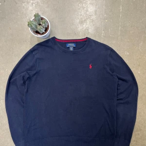  Polo Ralph Lauren Tröja  - Säljer denna snygga och tidlösa tröja från Polo Ralph Lauren i en mörkblå färg med röd brodyr. Perfekt för en stilren men avslappnad look!  🏷 Detaljer: 	•	Storlek: Mellan M & L (se mått nedan) 	•	Färg: Mörkblå med röd Polo-logga 	•	Material: Troligtvis 100 % bomull eller en mjuk bomullsblandning 	•	Skick: Mycket bra skick – inga synliga  fläckar.En klassisk och bekväm tröja som funkar till allt! ✨ Skickas snabbt och väl förpackad.  📩 Hör av dig vid frågor!. 