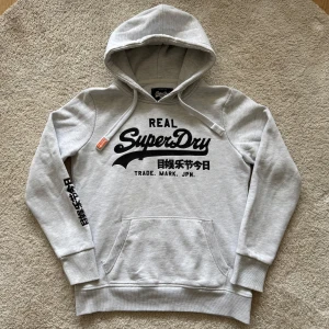 Superdry Hoodie Grå Herr Storlek M - Säljer en sjukt fin grå Superdry Hoodie i storlek M men passar bättre storlek S. Lätt att matcha och har en Vintage vibe. Hör av dig vid funderingar!🤩