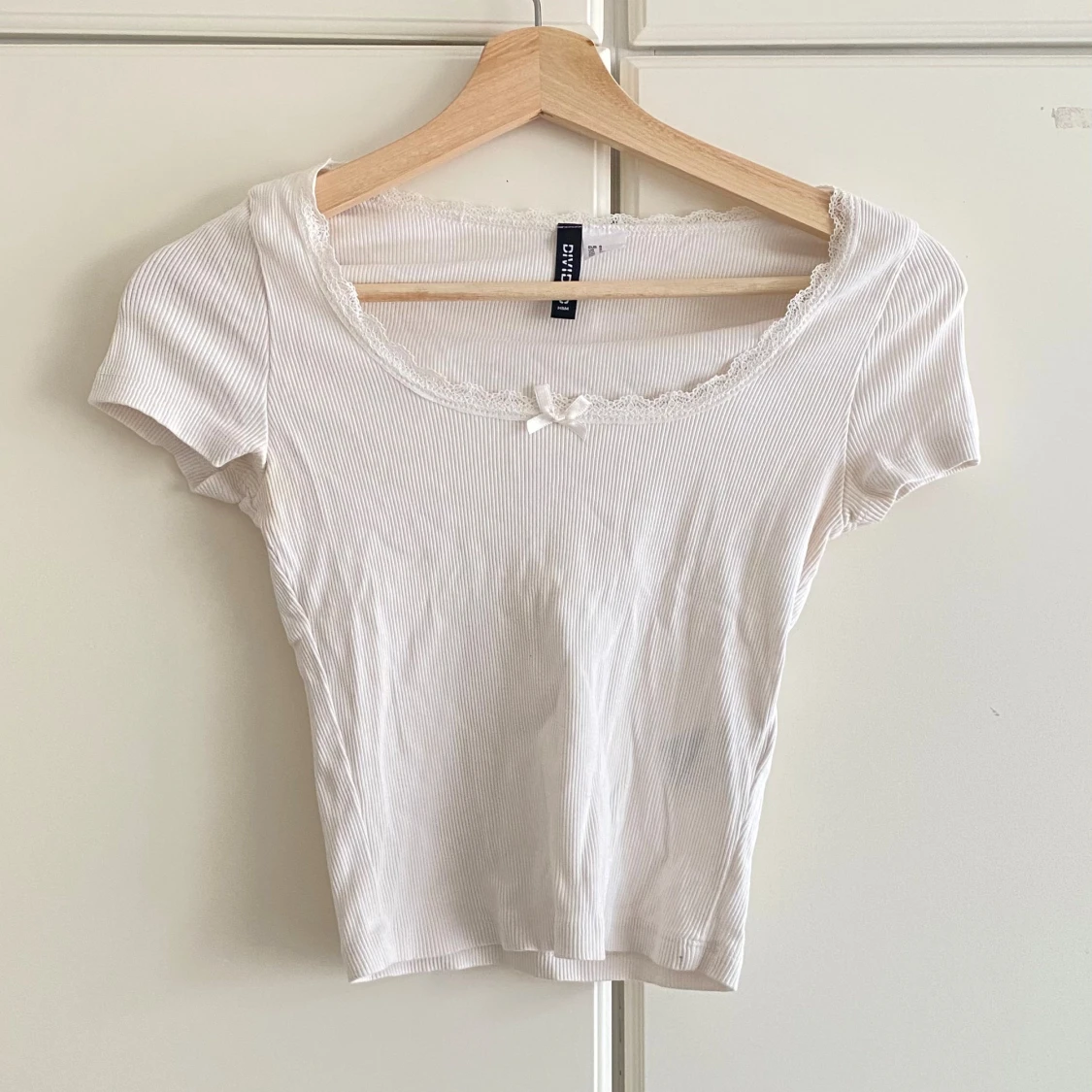 Vit ribbad topp med spets och rosett