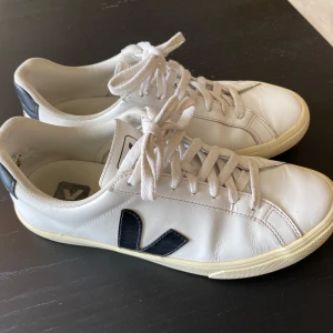 Vita Veja sneakers med svart V - Veja-sneakers i använt men bra skick förutom lite trasigt foder mitt bak (syns på bilderna). 
