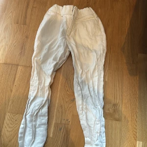 Vita linnebyxor med resårmidja - Snygga vita linnebyxor med resår i midjan och dragkedja fram. Byxorna har raka ben och fickor både fram och bak, där bakfickorna har knappar. Perfekta för en chill och luftig stil under varmare dagar.