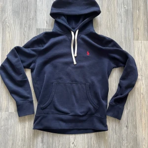 Mörkblå hoodie från Polo Ralph Lauren - Mörkblå hoodie från Ralph lauren i topp skick utan några som helst defekter. Köpt i början av sommaren men tyvärr urvuxen nu. Skriv vid frågor, funderingar eller bud!🙌vet inte varför bilderna blev upp och ner på