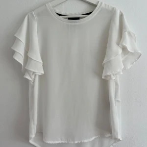 Blus - Supersöt vit blus från Object med volangärmar. Blusen är knappt använd så den är i väldigt fint skick, finns däremot en väldigt väldigt liten prick på magen men inget som syns tydligt. 