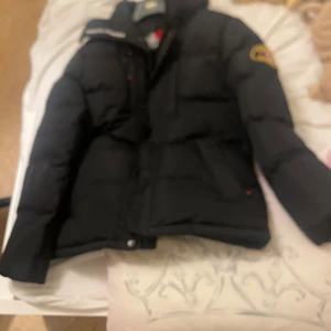 Svart pufferjacka Zavetti Canada  - Säljer en svart pufferjacka med huva och patch på ena ärmen i storlek S . Säljer den eftersom den har blivit för liten för mig pris-800kr pris i affär 2000kr pris kan diskuteras vid snabb affär 