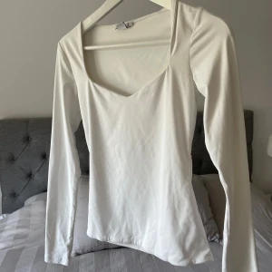 Vit långärmad topp med fyrkantig ringning - Säljer min vita långärmade topp med snygg fyrkantig ringning. Den är i storlek S och i mycket bra skick. Materialet är stretchigt och väldigt lent.