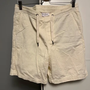 Lindbergh ljusa manchester shorts - Snygga ljusbeige shorts från Lindbergh i mjuk manchester. De har elastisk midja med snörning, två sidofickor och två bakfickor. Aldrig använt dom men dom e lite skrynkliga då jag har vikt dom slarvigt men det är bara att tvätta dom så blir dom bra igen. Dom är st L ”relaxt fit” fast dom passar mera M, vet inte varför dom ljuger om relaxt fit men aja tveka inte på att höra av er vid funderingar 