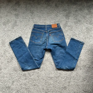 Levi's 501 blå jeans L30 - Klassiska Levi's 501 jeans i blå denim med raka ben och femficksmodell. Snyggt slitna detaljer och ikonisk läderpatch bak i midjan. Passar dig som gillar tidlös stil och vill ha ett par jeans som funkar till allt. Stängs med knappgylf.