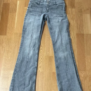 Grå low bootcut jeans från Gina Tricot young  - Snygga grå jeans från Gina Tricot i storlek 152. Modellen är ultra low rise, har bootcut-ben, framfickor med markerade sömmar och klassiska bakfickor. Jeansen är i mjuk denim med en cool tvättad look och passar perfekt till en trendig vardagsstil. Jeansen är i näst intill nyskick.