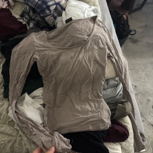 Beige långärmad topp ginatricot - Säljer en beige långärmad topp med omlott-skärning och mjukt, tunt material. Perfekt för lager-på-lager och passar till både jeans och kjol. Snyggt avslappnad passform och neutral färg som funkar till allt.