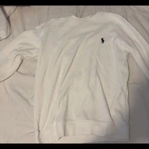 Vit sweatshirt från Ralph Lauren - Klassisk vit sweatshirt från Ralph Lauren med den ikoniska broderade loggan på bröstet. Tröjan har rund halsringning och långa ärmar. Perfekt basic att ha i garderoben och lätt att matcha med allt.