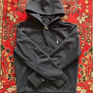 Mörkblå Ralph Lauren hoodie - Säljer denna fina hoodie från Ralph Lauren då jag inte använder den. I nyskick, sparsamt använd. Hör av dig för eventuella frågor!