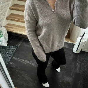 Beige stickad tröja med krage - Mysig beige stickad tröja med krage och tre knappar framtill. Tröjan har lång ärm och en relaxed passform. Ribbstickade muddar vid ärmslut och nederkant.