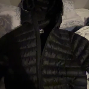 Svart dunjacka från McKinley - Säljer en svart dunjacka från McKinley i storlek 158/164. Jackan har huva, quiltad design och dragkedja framtill. Perfekt för kalla dagar med sin lätta och värmande känsla. Stilren look som funkar till det mesta.