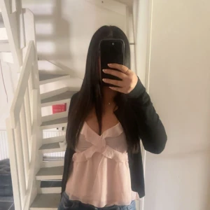 Ljusrosa volangig linnetopp - Supersöt ljusrosa linnetopp med volangdetaljer och v-ringning. Toppen är ärmlös.