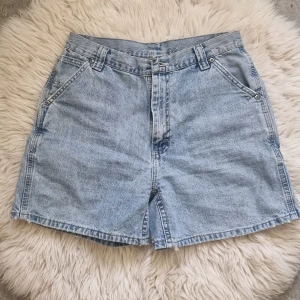 Ljusblå jeansshorts från Lee, M - Säljer ett par klassiska ljusblå jeansshorts från Lee i storlek M. De är högmidjade med raka ben, har fickor fram och bak samt bälteshällor. Perfekta för sommaren och tillverkade i slitstarkt denimtyg.