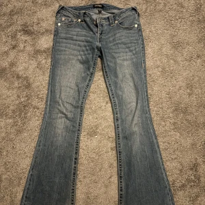 True Religion jeans ultra low rise joey flare sn - Säljer ett par jättesnygga jeans från True Religion som är från Nelly, dom är använda ganska mycket men kommer inte så mycket till användning längre, det är i storlek 27 vet inte direkt va det är för storlek om de är S eller M, dom har rosa detaljer, skriv för mer bilder eller om ni har frågor och pris går att diskutera☺️