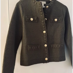 Olivgrön stickad kofta med guldknappar från hm - Snygg olivgrön stickad kofta med dekorativa guldknappar framtill och på fickorna. Koftan har rund halsringning, långa ärmar och fyra fickor som ger en cool vintagekänsla. Perfekt att slänga över en t-shirt eller linne för en chill look.