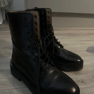 Svarta kängor i skinn, storlek 39 - Ett par svarta kängor/boots i skinn från & other stories, storlek 39. De har snörning hela vägen upp, grov platt sula och rund tå. 