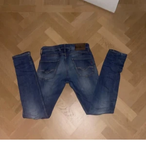 Blå jeans från reaplay - Säljer ett par klassiska blå jeans från Levi's med snygg slitning och raka bakfickor. Jeansen har en normal passform och är tillverkade i slitstarkt denim. Perfekta för dig som gillar en tidlös look.