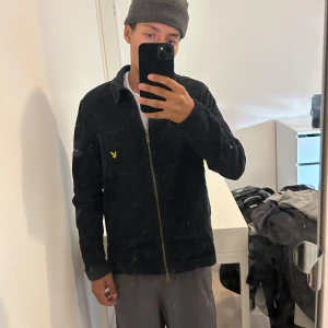 Marinblå manchester overshirt från Lyle & Scott - Marinblå manchester overshirt från Lyle & Scott med gul broderad logga på bröstfickan. Jackan har dragkedja framtill, klassisk krage och raka ärmar. Perfekt för lager-på-lager och snygg till jeans. Använt endast 5 gånger max och inga skador, säljer då den inte kommer till användning 