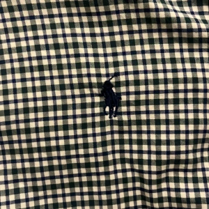 Rutig skjorta Polo Ralph Lauren slim fit - Snygg rutig skjorta från Polo Ralph Lauren i slim fit. Skjortan är blå och vit med klassiskt rutmönster och har broderad logga på bröstet. Tillverkad i mjuk bomull och har knappar framtill. Perfekt för dig som gillar stilren och tidlös look.
