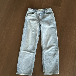 Levi's 501 ljusblå raka jeans - Klassiska Levi's 501 jeans i ljusblå tvätt med raka ben och normal passform. Jeansen har fem fickor, knappgylf och den ikoniska röda Levi's-taggen bak. Perfekta för en avslappnad och tidlös look.