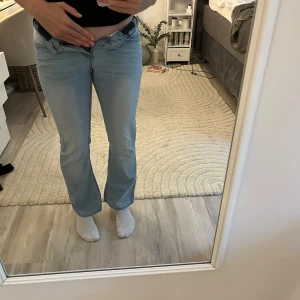 Ljusblå bootcut jeans från LAB Industries - Säljer ett par ljusblå jeans från LAB Industries i klassisk bootcut-modell. Jeansen har super låg midja och är bootcut Tillverkade i mjukt denimtyg som är skönt att bära. Perfekta för dig som gillar en avslappnad och trendig look.