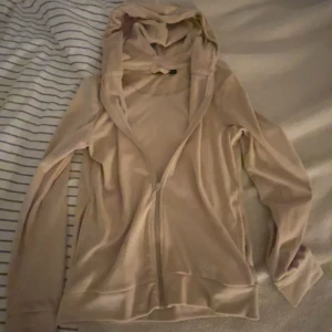 Beige hoodie med dragkedja - Snygg beige hoodie med dragkedja framtill och huva. Tröjan har långa ärmar och är tillverkad i ett mjukt, tunt material som känns skönt mot huden. Perfekt för lager-på-lager och chill dagar.