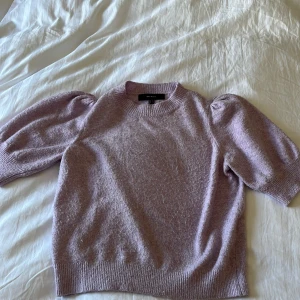 Ljuslila stickad tröja Vero Moda - Superfin ljuslila stickad tröja från Vero Moda med puffiga halvlånga ärmar och rund halsringning. Tröjan har en mjuk och mysig känsla. Snygg ribbad kant vid ärmslut och nederkant. Lite nopprig, färgen stämmer inte riktigt me bilderna.