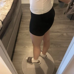 Svarta tighta träningsshorts - Svarta, tighta träningsshorts med hög midja. Perfekta för gymmet eller löpning. Stretchigt material som sitter skönt och följer kroppen. Enkel och stilren design utan synliga detaljer.