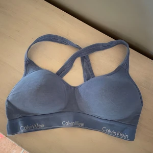 Blå sport-bh från Calvin Klein - Säljer en blå sport-bh från Calvin. Den har elastiska band och är väldigt bekväm. Passar tyvärr inte längre,  inte använd särskilt många gånger och är i ett bra skick . 🩵💙ordinarie pris ligger runt 500kr 