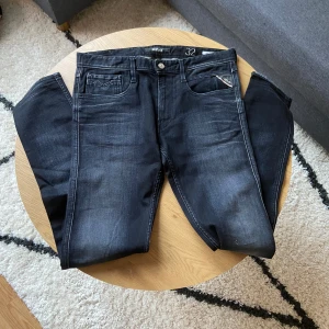Svarta Replay jeans - Tjenare👋 Säljer ett par svarta Replay jeans i klassisk femficksmodell och i Anbass modell. Jeansen har raka ben, silverfärgade detaljer och tydliga slitningar för en cool look😮‍💨  Passar perfekt till dig som gillar stilrena och tidlösa jeans⏱️  Skönt material och har inga defekter!🙏  Storleken är W32 L34📐  Priset kan diskuteras vid snabb affär!💸  Vid några frågor: Meddela📩