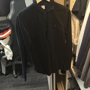 Skjorta från Lindex - Säljer en marinblå skjorta från Lindex i storlek 170. Skjortan har klassisk krage, knäppning framtill och en bröstficka. Perfekt för dig som gillar en enkel och stilren look.