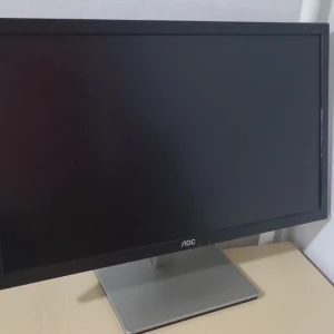 AOC 24-tums datorskärm - Säljer en svart AOC datorskärm på 24 tum med bred rektangulär form och silverfärgad fot. Skärmen har anslutningar för DVI, VGA och HDMI på baksidan. Perfekt för gaming eller arbete vid skrivbordet.