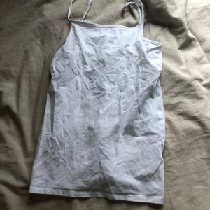 Vit linnetopp från H&M - Säljer en enkel och stilren vit linnetopp från H&M med smala axelband. Toppen är i mjuk bomull och har en rak passform. Har 3st exakt likadana om någon är intresserad.