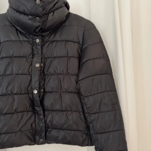 Svart pufferjacka med hög krage - Säljer en svart pufferjacka med hög krage och tryckknappar framtill som liknar Herno jackorna.  🤗😍😛🖤