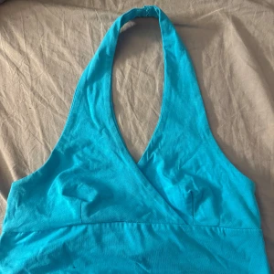 Turkos halterneck topp från FB Sister - Säljer en turkos halterneck topp från FB Sister i storlek M. Toppen har omlott-skärning framtill.. Perfekt för varma dagar och somriga outfits!