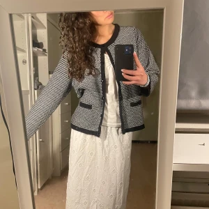 Svartvit cardigan jacka med mönster från Isolde - Säljer en svartvit cardigan jacka med diskret mönster och svarta kanter. Köpt secondhand, saknar storlekslapp men sitter som en s/m på mig som bär storlek s-m. Perfekt att slänga på vid kallare sommardagar/vår/höst! 