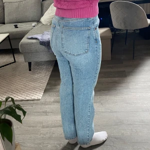 Ljusblå raka jeans - Säljer ett par ljusblå jeans med klassisk femficksdesign och raka ben. Jeansen har hög midja och stängs med dragkedja och knapp. 
