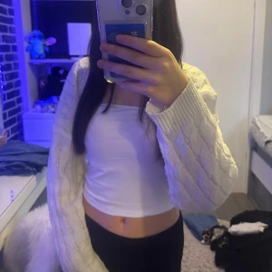 Vit stickad bolerotopp - Säljer en vit stickad bolerotopp med kabelstickat mönster. Toppen har lång ärm och är croppad, passar och ha över ett linne eller en crop top. Säljer på grund av att jag redan har 2 andra och denna inte kommer till användning. Säljer för 100kr