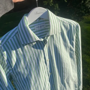Grön- och vitrandig skjorta från John Henric - Snygg skjorta med gröna och vita ränder från John Henric. Klassisk krage och knäppning framtill. Perfekt för dig som gillar stilrena och fräscha plagg med lite färg. Skjortan har lång ärm och normal passform.